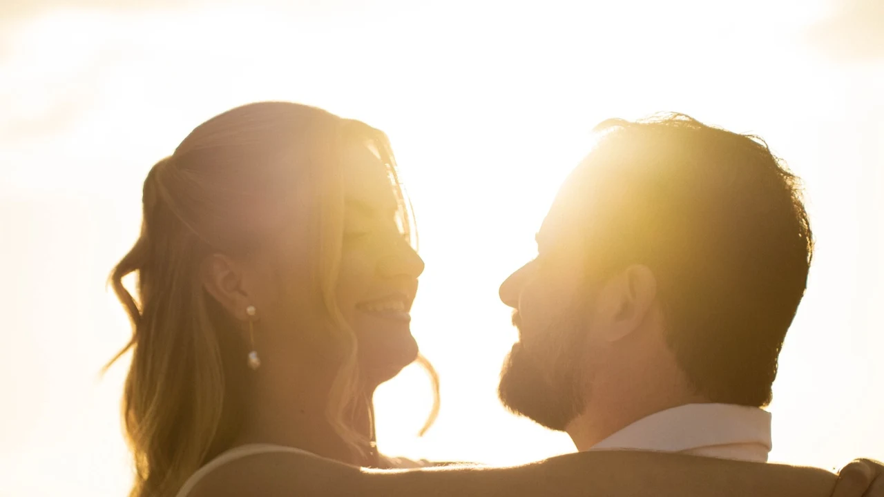 Silhueta e contraluz do casal ao entardecer com luz dourada e sorriso espontâneo
